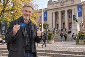 En person visar ett SkimSkydd RFID-skyddskort och gör tummen upp utanför Göteborgs universitet i Vasaparken